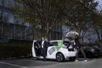 Two men with a GreenMobility car, one opening the trunk and another alighting from the car.